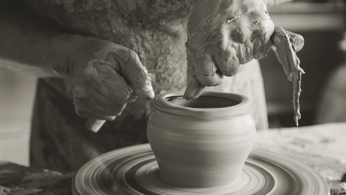 A potter's hands shaping clay on a wheel