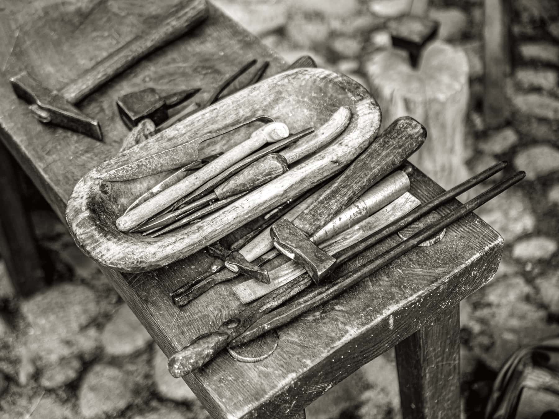 A maker's workbench with hand tools laid out on worn timber